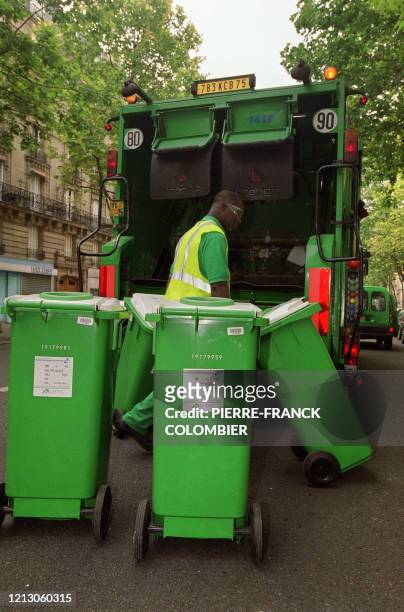 Un employé de la ville de Paris replace des poubelles destinées au verre , après les avoir vidées dans la benne du camion, en août 2002 à Paris.