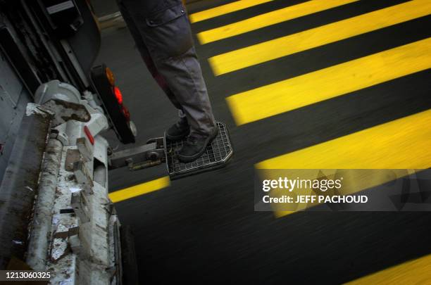 Dustman stands on the footboard of a waste truck, 06 July in Lyon, south France. Un éboueur se trouve sur le marchepieds d'un camion-poubelle, le 06...