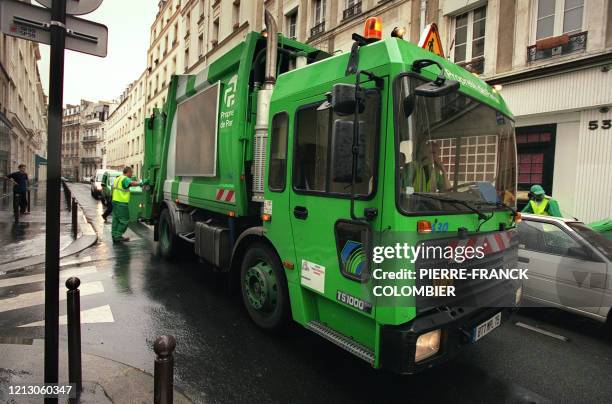 Un employé de la ville de Paris vide des poubelles destinées aux ordures ménagères dans la benne du camion, en août 2002 à Paris.