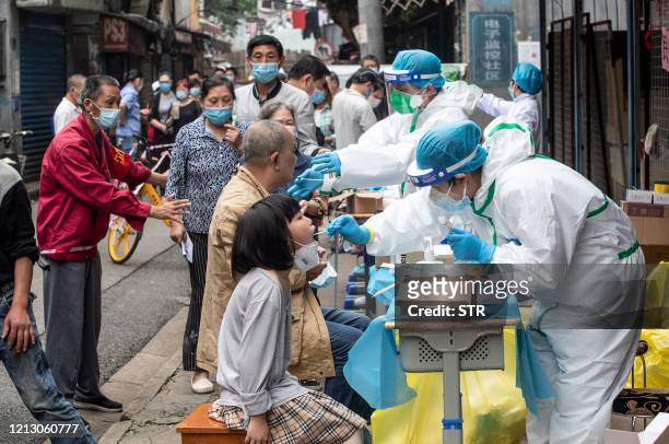 Medical workers take swab samples from residents to be tested for the COVID-19 coronavirus, in a street in Wuhan in China's central Hubei province on...