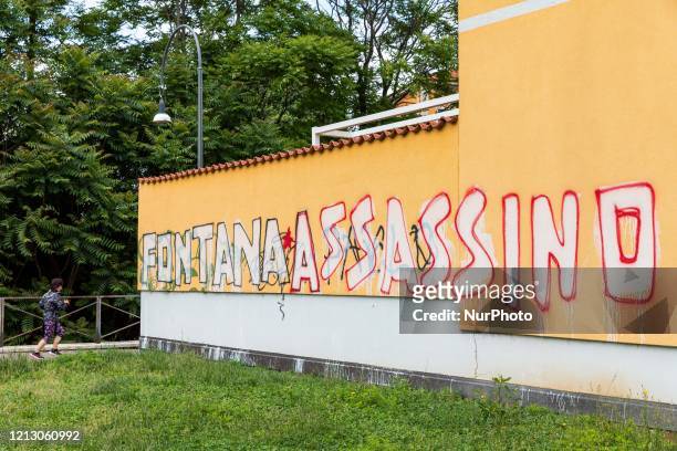 Runner runs beside the graffito Fontana assassino that appeared on a wall of a building in Via Vittorelli claimed by the party P.CARC during the...