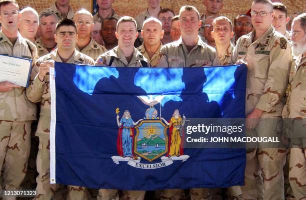 Troops stationed at Bagram pose with a New York State flag offered by New York Governor George Pataki, at the Bagram air base, 11 April 2002. The...