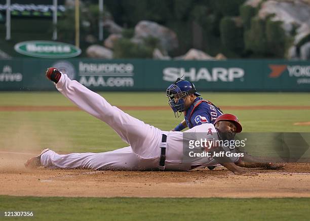 Torii Hunter of the Los Angeles Angels of Anaheim slides safely past the tag of catcher Yorvit Torrealba of the Texas Rangers and scores a run in the...