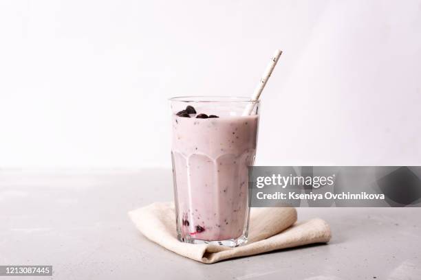 two glasses of blueberries smoothie on pink background. poring from blender into glass. - smoothie sparse stock pictures, royalty-free photos & images