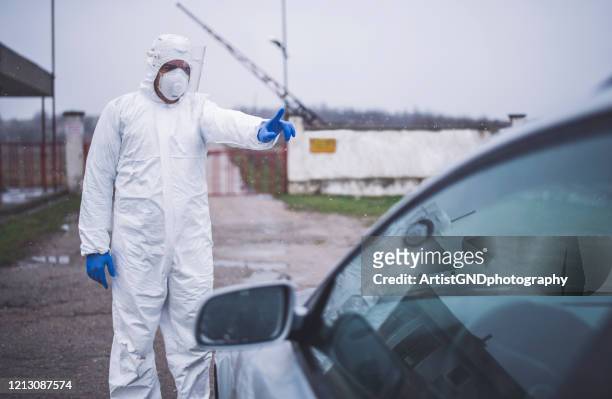 mann mit schutzanzug kontrolle grenzverkehr, geschlossene grenze virus pandemie - autostop stock-fotos und bilder