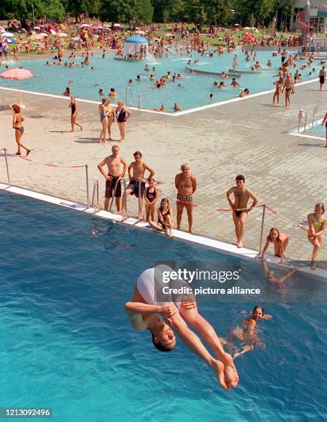 Ein junger Mann springt am 11.8.1998 in einem Münchner Freibad vom drei Meter-Brett kopfüber ins kühle Nass. Wer Zeit hat verbringt sie bei...