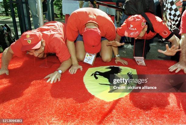 Drei Ferrari Fans huldigen am 31.7.98 am Rande des Hockenheimrings einen Ferrari-Teppich, den sie auf dem Boden ausgebreitet haben. Zum Grand Prix...