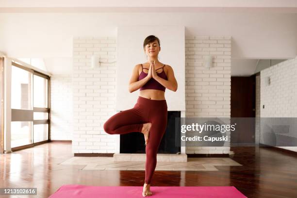 yoga instructor doing vrikshasana and smiling - tree position stock pictures, royalty-free photos & images