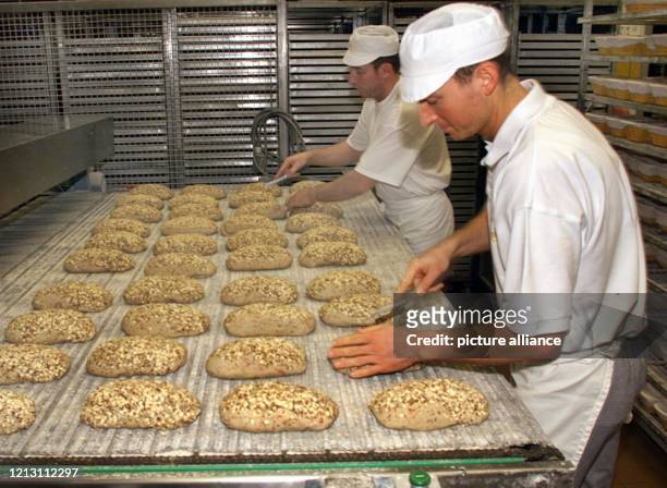 Zwei Mitarbeiter der Großbäckerei Kamps AG bereiten am im nordrhein-westfälischen Schwaltal am Förderband Brote zum Backen vor. In dem Werk in...