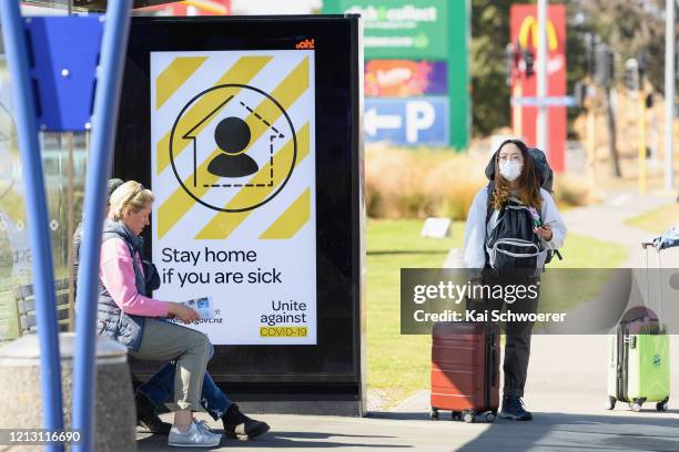 Traveller wearing a protective mask is seen waiting for a bus near Christchurch International Airport on March 18, 2020 in Christchurch, New Zealand....