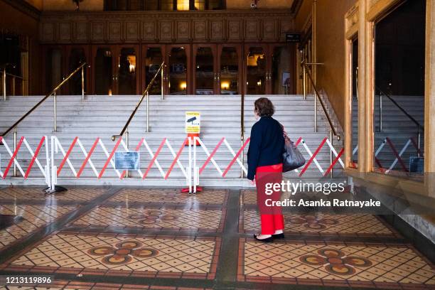 Woman stands at the entrance of the Regent Theatre complex which has been shutdown due to COVID-19 on March 18, 2020 in Melbourne, Australia. The...