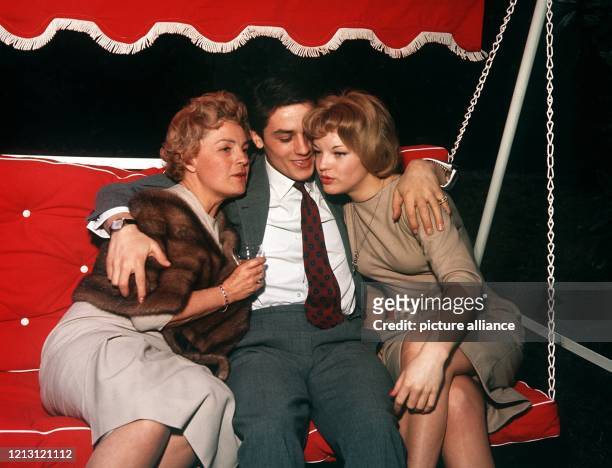 Alain Delon sitzt auf einer Hollywoodschaukel zwischen Magda Schneider und seiner Verlobten Romy Schneider . Der französische Schauspieler und...