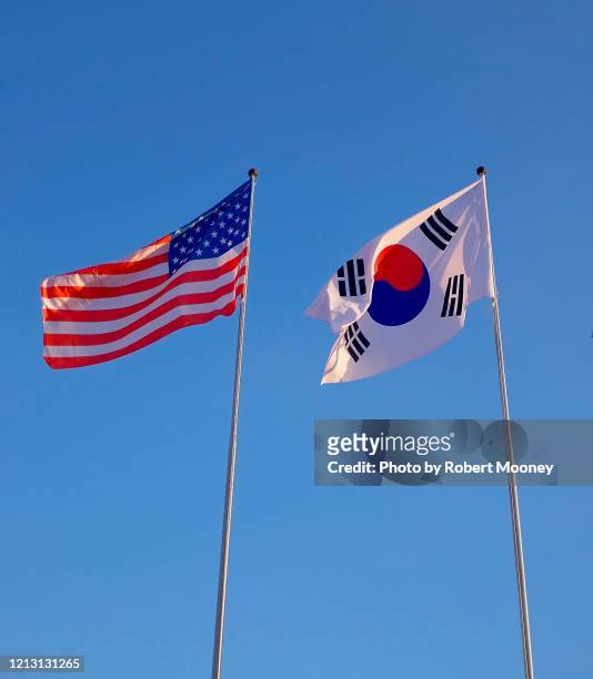 flags of the united states and south korea, against a blue sky - corea del sur fotografías e imágenes de stock