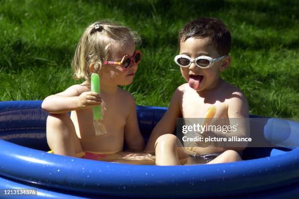 Lässig entspannen sich Nina und Leo am 15.5.2000 in Widdersdorf bei hochsommerlichen Temperaturen im Planschbecken mit einem erfrischenden Wassereis.