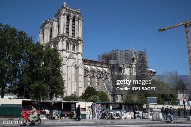 People walk past the open stands of the booksellers, also called bouquinistes, by Notre-Dame Cathedral in Paris, on May 15 as France eases the...