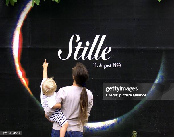 Eine Mutter betrachtet mit ihrem Kind am 10.8.1999 in Karlsruhe ein Werbeplakat, das eine totale Sonnenfinsternis zeigt. Trotz vieler Wolken hat die...