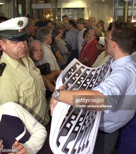 Unter Polizeischutz trägt ein Optiker am 10.8.1999 in Dortmund Bögen mit aufgedruckten Brillengestellen an wartenden Kunden vorbei. Der Optiker bot...