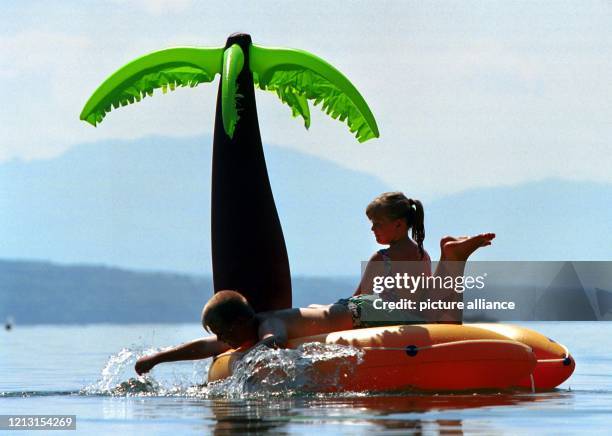 Scharf zeichnen sich am 4.8.1999 die Silhouetten zweier Kinder und ihrer schwimmenden Palmen-Badeinsel auf dem oberbayerischen Starnberger See ab....