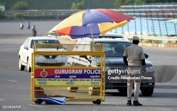 Police personnel screens vehicles crossing barricades placed along the Gurugram-Delhi Sirhaul border at National Highway-48 near Ambience Mall during...