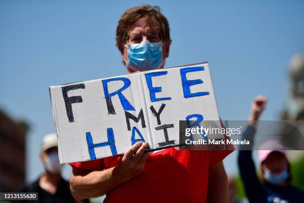 Demonstrator holds a placard stating "FREE MY HAIR" while allying outside the Pennsylvania Capitol Building to protest the continued closure of...