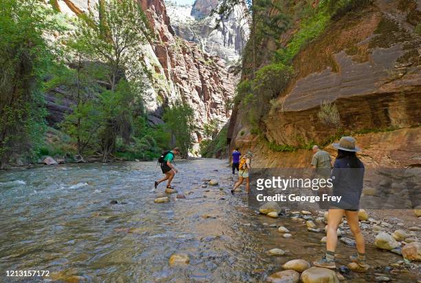Hikers take pictures at the entrance of the famous Narrows hike, currently closed, along the North Fork of the Virgin River in Zion National Park on...