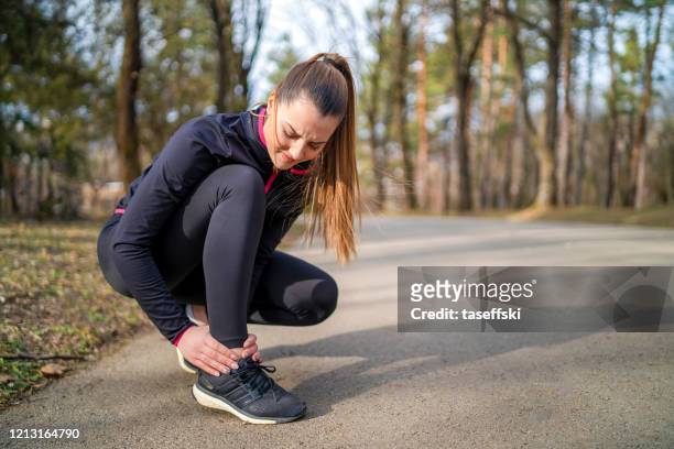 runner girl is holding her injured leg - injured runner stock pictures, royalty-free photos & images