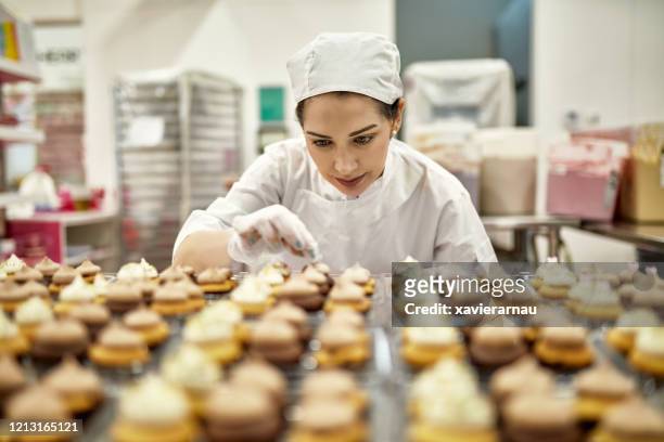 hispanic american female baker decorating vegan cupcakes - food and drink industry stock pictures, royalty-free photos & images