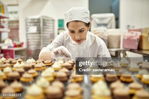 Padeiro hispânico-americano decorando cupcakes veganos Padeiro hispânico-americano decorando cupcakes veganos