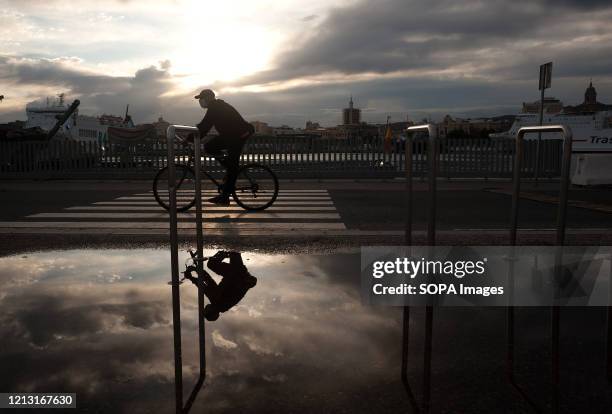 Man rides a bicycle at the deserted commercial area 'Muelle Uno' during the partial lockdown after the beginning of phase 1 in some cities. Spain is...