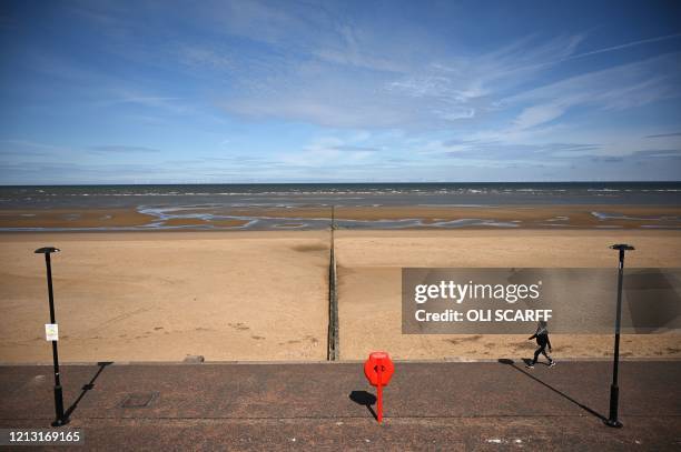 Woman takes her daily excercise on the promenade alongside a deserted beach in Rhyl, north Wales on May 16 following an easing of lockdown rules in...