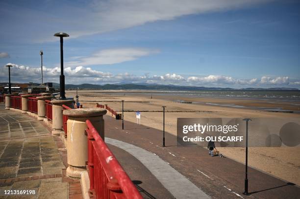 A dog walker takes daily excercise on the promenade alongside a deserted beach in Rhyl, north Wales on May 16 following an easing of lockdown rules...