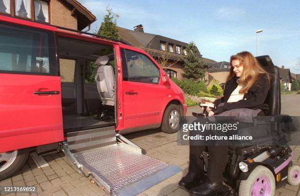 Mit ihrer rechten Hand an der Fernbedienung öffnet Monyc Trautz die Tür ihres neuen Autos und fährt den Lift aus, der ihren elektrischen Rollstuhl...