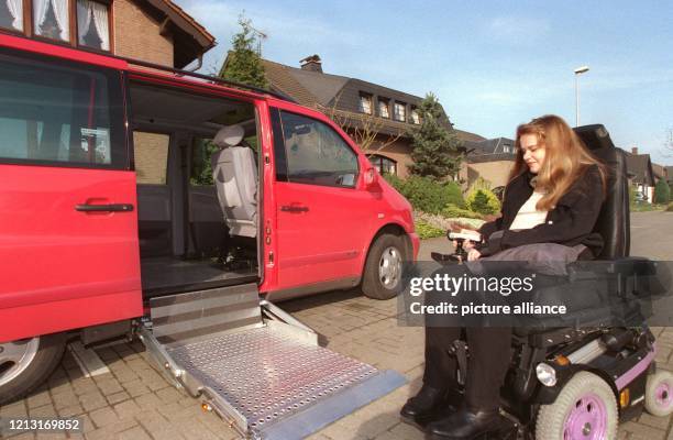 Mit ihrer rechten Hand an der Fernbedienung öffnet Monyc Trautz die Tür ihres neuen Autos und fährt den Lift aus, der ihren elektrischen Rollstuhl...