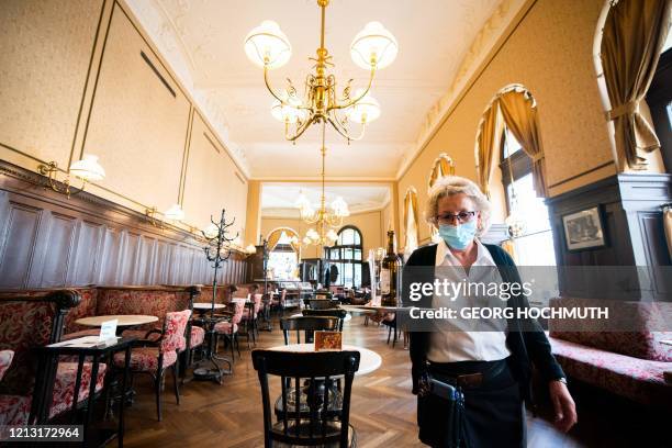 Waitress wearing a face mask carries a tray at Cafe Sperl in Vienna, Austria, on May 16 after restrictions were eased amid the novel coronavirus /...
