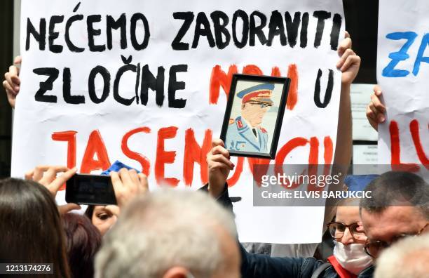 People, some wearing protective face masks against the novel coronavirus, COVID-19, and another holding a portrait of Communist leader Josip Broz...