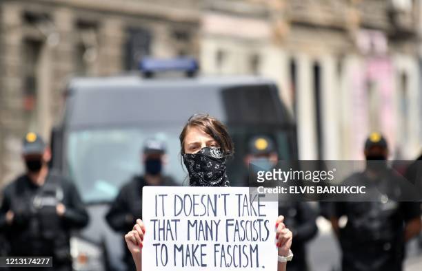 Woman holds a sign as people, some wearing protective face masks against the novel coronavirus, COVID-19, gather in Sarajevo's city center to protest...
