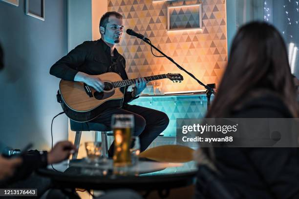 homme jouant la guitare acoustique et chantant sur l’étape - guitariste photos et images de collection