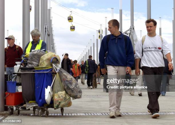 Mit einem Seitenblick verfolgen zwei junge Expo-Besucher am 11.7.2000 die Arbeit eines Mitarbeiters der Abfallentsorgung auf der Exponale-Brücke der...