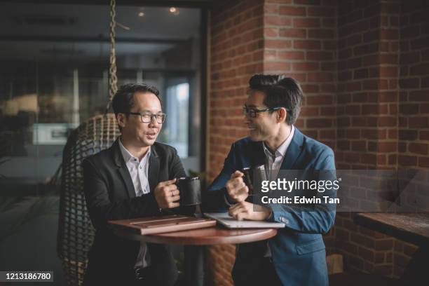 2 asian chinese white collar workers having discussion during their coffee break in lounge using laptop and digital tablet - two executive man coffee shop stock pictures, royalty-free photos & images