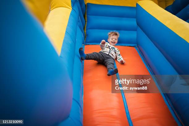 弾む城に滑り落ちるかわいい男の子 - inflatable playground ストックフォトと画像