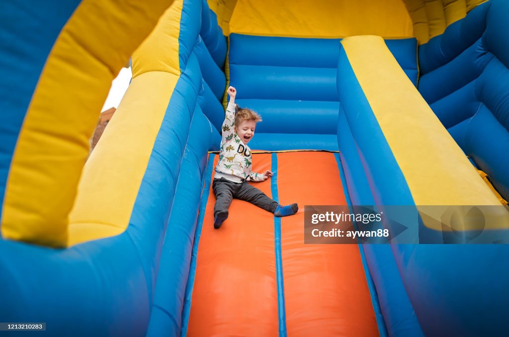 Junge rutscht auf eine Hüpfburg