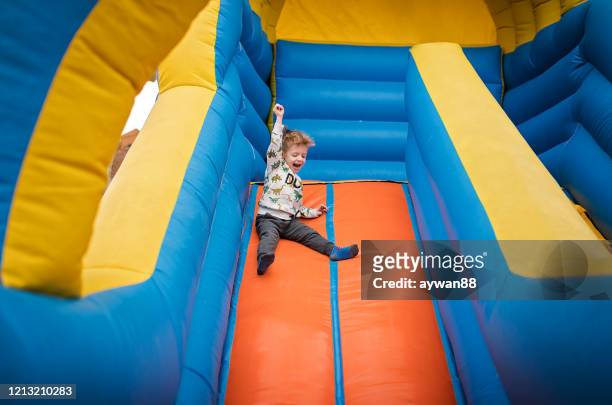 boy sliding down on a bouncy castle - inflatable playground stock pictures, royalty-free photos & images