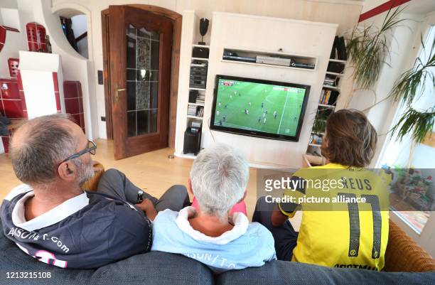 May 2020, Bavaria, Rieden: A family in an apartment watches the conference call of first division matches of the Sky television channel on their...