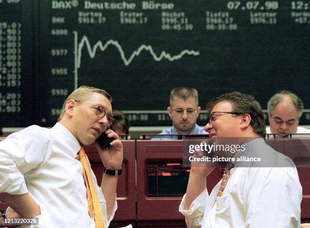 Aktienhändler mit Handy unter der Dax-Kurve am 7.7.1998 in der Frankfurter Börse. Die Rekordfahrt des Deutschen Aktien-Indexes endete fürs erste...
