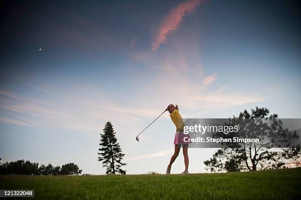 teen girl makes a powerful drive on a golf course - mini golf stock-fotos und bilder