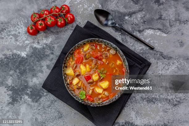 bowl of sausage goulash with potatoes, tomatoes, bell peppers, leek and parsley - bell pepper stock-fotos und bilder