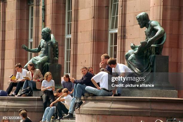 Studenten sitzen im Eingangsbereich der Universität in Freiburg auf der Treppe und zu Füßen der antiken Gelehrten Homer und Aristoteles, aufgenommen...