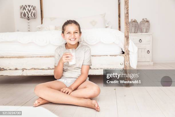 portrait of smiling girl sitting on the floor at home drinking glass of milk - shabby chic stock pictures, royalty-free photos & images