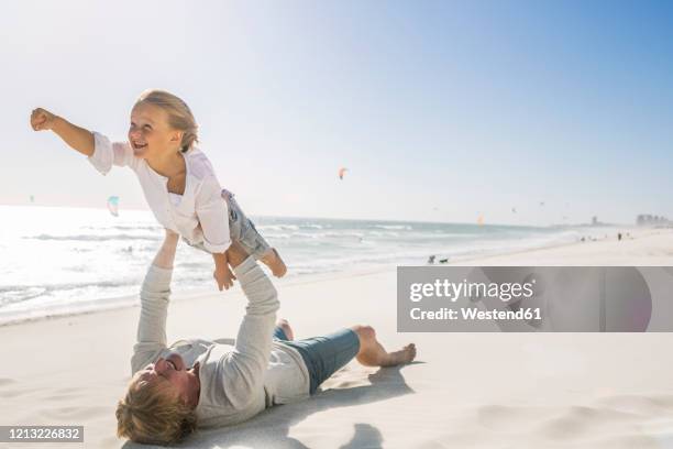 father having fun with his son on the beach, pretending to fly - 飛行機のまね ストックフォトと画像