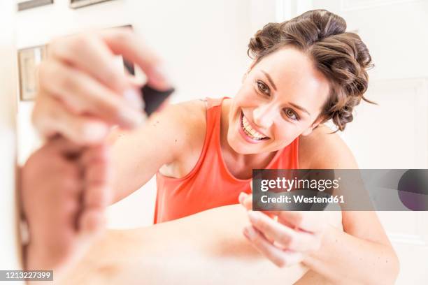 portrait of happy woman with curlers  painting toenails - painting toenails stock-fotos und bilder